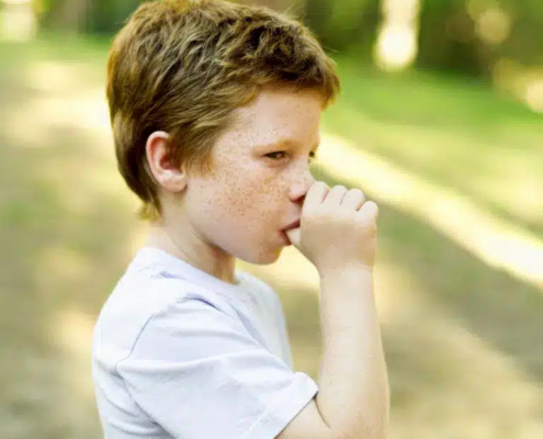 Thumb sucking blog featured image of a young boy sucking his thumb outdoors.