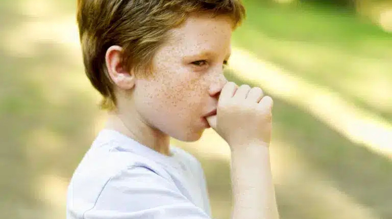 Thumb sucking blog featured image of a young boy sucking his thumb outdoors.